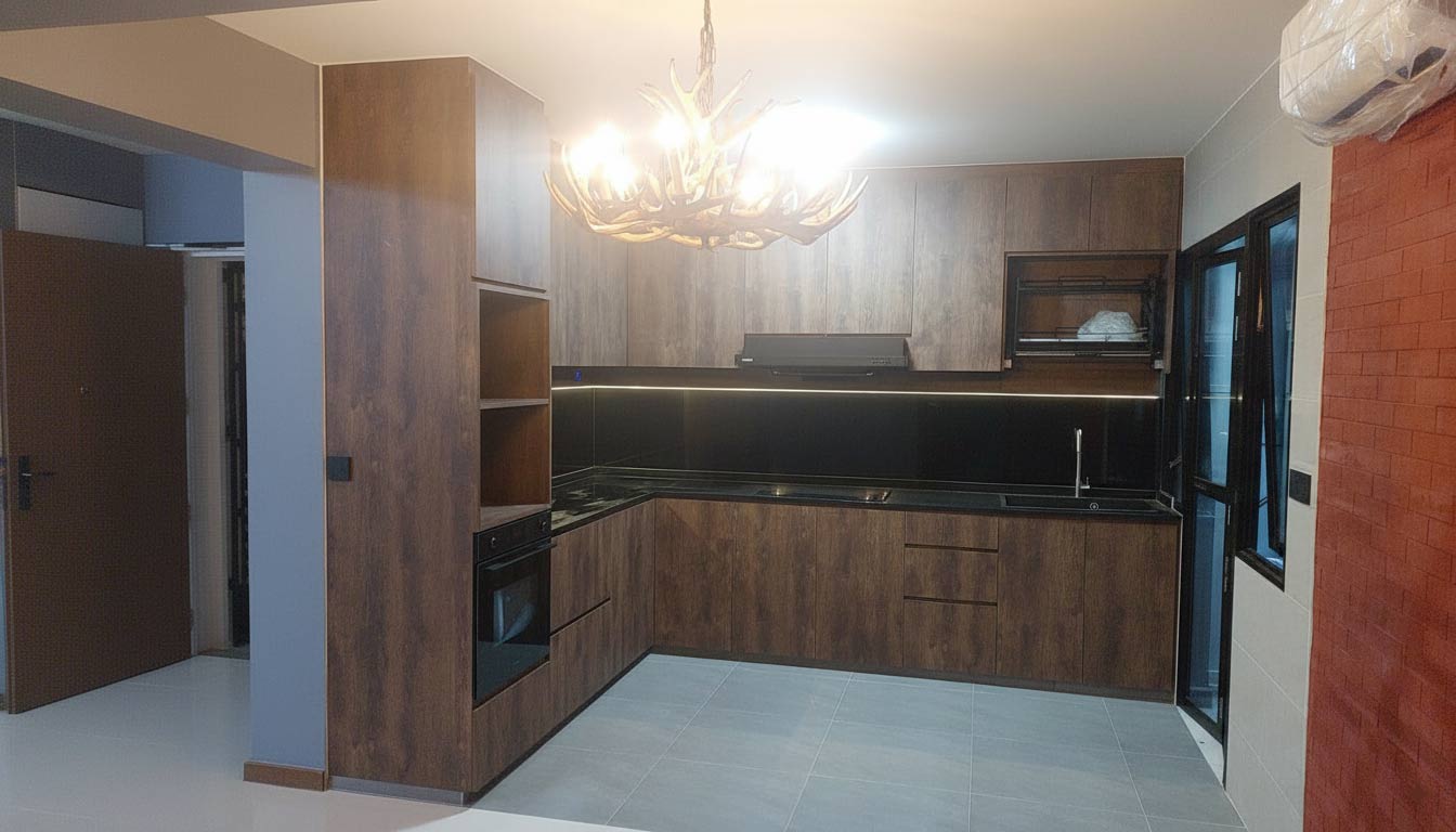 A kitchen in Singapore with a white marble countertop and backsplash with gold veins, under-cabinet lighting, and a black stovetop, highlighting a Home Renovation.