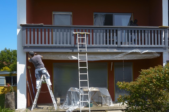 Construction worker rappelling down the side of a tall building while painting the exterior, illustrating the preparation and labor that dictates a typical painting service timeline.